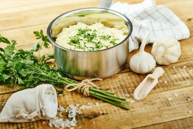 lezzetli ve kremalı taze patates püresi ahşap bir masa üzerinde gümüş bir tencerede maydanoz serpilir