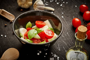 kiraz domates mozzarella ve fesleğen siyah ahşap bir masa üzerinde bir kase ile lezzetli salata