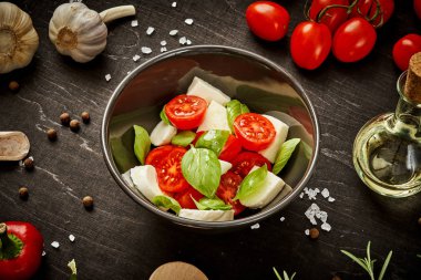 kiraz domates mozzarella ve fesleğen siyah ahşap bir masa üzerinde bir kase ile lezzetli salata