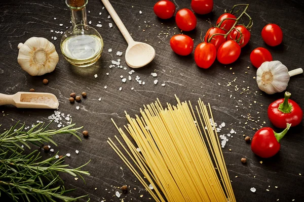 malzemeler için pişirme oluşan domates, sarımsak, tuz, yemek zeytin biber ve makarna üzerine siyah bir tablo