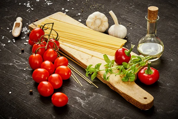 malzemeler için pişirme oluşan domates, sarımsak, tuz, yemek zeytin biber ve makarna üzerine siyah bir tablo