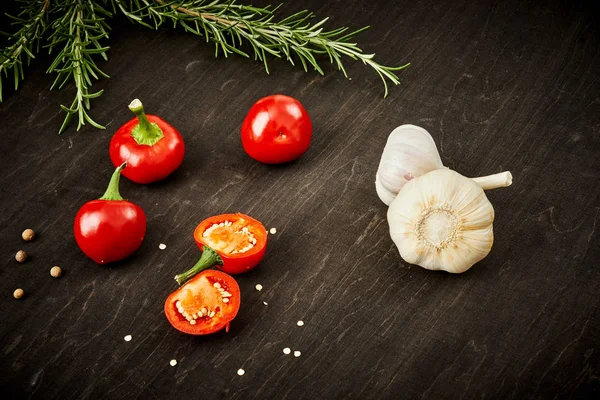 taze ve baharatlı kırmızı biber, sarımsak ve biberiye siyah ahşap bir masa üzerinde