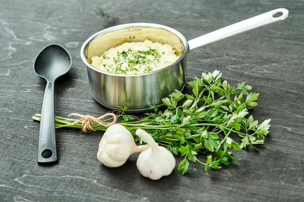 lezzetli ve kremalı taze patates püresi siyah bir tabloda gümüş bir tencerede maydanoz serpilir