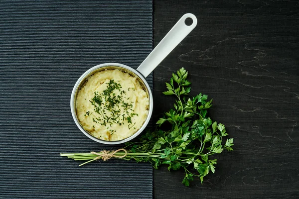 lezzetli ve kremalı taze patates püresi siyah bir tabloda gümüş bir tencerede maydanoz serpilir