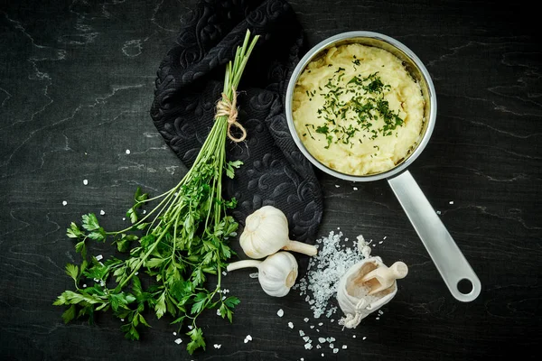 lezzetli ve kremalı taze patates püresi siyah bir tabloda gümüş bir tencerede maydanoz serpilir
