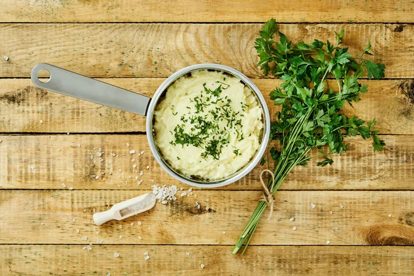 lezzetli ve kremalı taze patates püresi ahşap bir masa üzerinde gümüş bir tencerede maydanoz serpilir
