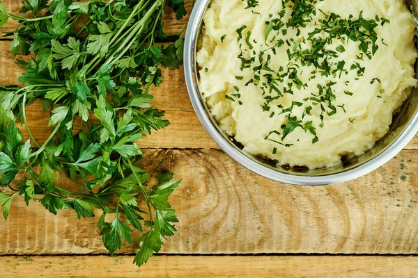 lezzetli ve kremalı taze patates püresi ahşap bir masa üzerinde gümüş bir tencerede maydanoz serpilir