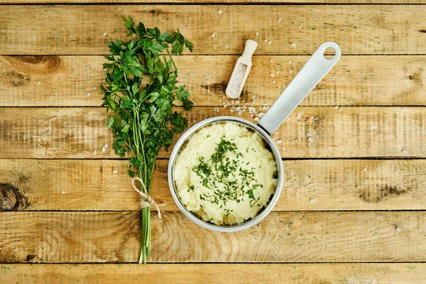 lezzetli ve kremalı taze patates püresi ahşap bir masa üzerinde gümüş bir tencerede maydanoz serpilir