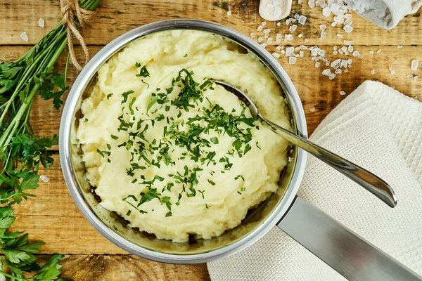 lezzetli ve kremalı taze patates püresi ahşap bir masa üzerinde gümüş bir tencerede maydanoz serpilir
