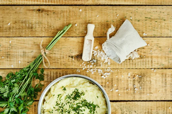 lezzetli ve kremalı taze patates püresi ahşap bir masa üzerinde gümüş bir tencerede maydanoz serpilir