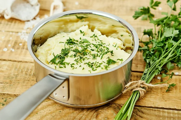 lezzetli ve kremalı taze patates püresi ahşap bir masa üzerinde gümüş bir tencerede maydanoz serpilir