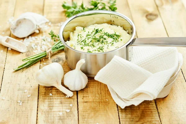 lezzetli ve kremalı taze patates püresi ahşap bir masa üzerinde gümüş bir tencerede maydanoz serpilir