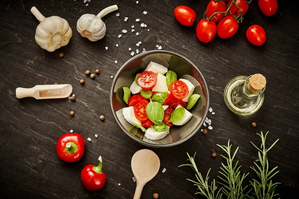 kiraz domates mozzarella ve fesleğen siyah ahşap bir masa üzerinde bir kase ile lezzetli salata