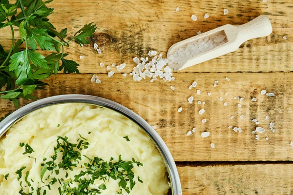 lezzetli ve kremalı taze patates püresi ahşap bir masa üzerinde gümüş bir tencerede maydanoz serpilir