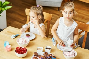 iki güzel kız kardeş beyaz elbise süslemeleri ve lezzetli kek yemek