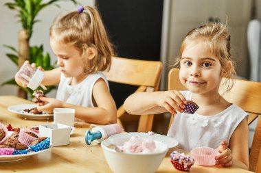 iki güzel kız kardeş beyaz elbise süslemeleri ve lezzetli kek yemek