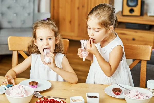 Iki güzel kız kardeş beyaz elbise süslemeleri ve lezzetli kek yemek — Stok fotoğraf