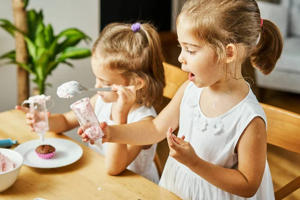 iki güzel kız kardeş beyaz elbise süslemeleri ve lezzetli kek yemek