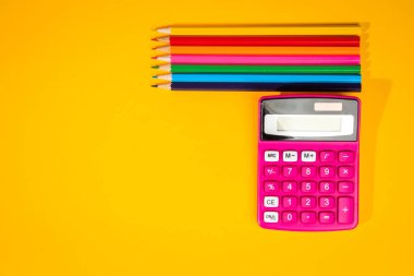 sarı arka plan ile bir boya kalemi, hesap makinesi, cetvel ve keçeli kalemler