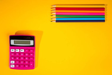 sarı arka plan ile bir boya kalemi, hesap makinesi, cetvel ve keçeli kalemler