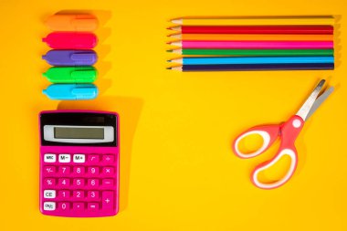 sarı arka plan ile bir boya kalemi, hesap makinesi, cetvel ve keçeli kalemler