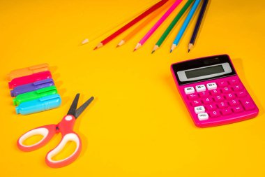 sarı arka plan ile bir boya kalemi, hesap makinesi, cetvel ve keçeli kalemler