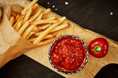 çıtır çıtır patates kızartması ve baharatlı kırmızı sos siyah bir eski tablo