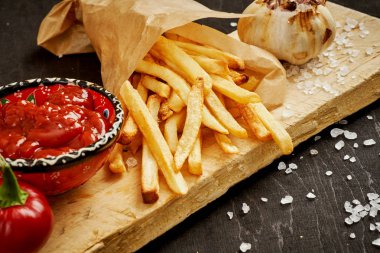 çıtır çıtır patates kızartması ve baharatlı kırmızı sos siyah bir eski tablo