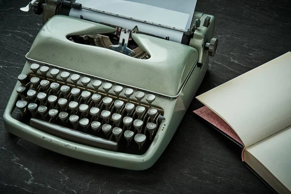 Bela velha máquina de escrever cinza e livro em uma mesa preta — Fotografia de Stock
