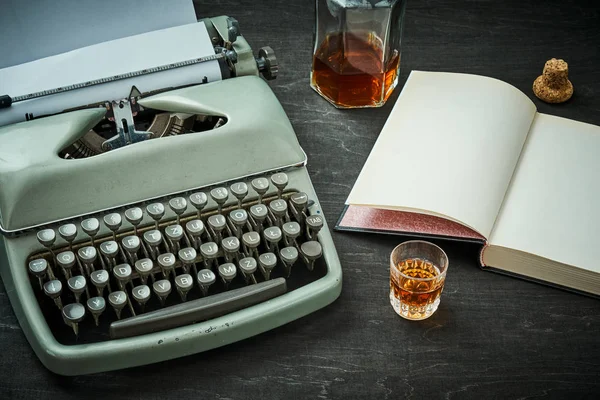 Bela velha máquina de escrever cinza, livro e um copo com álcool — Fotografia de Stock