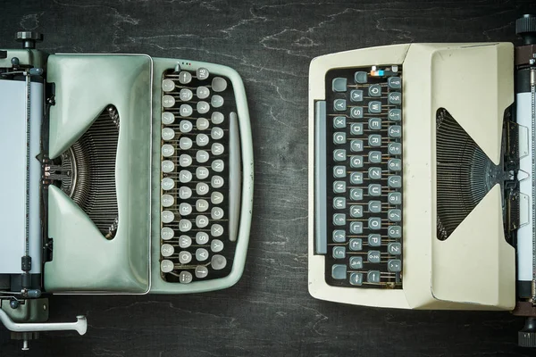 Två gamla skrivmaskiner på ett svart bord — Stockfoto