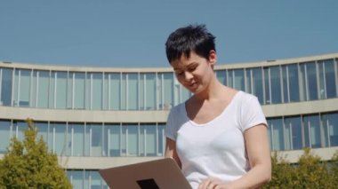 bina ve bir bilgisayarda çalışan bir işyeri önünde oturan genç iş kadını
