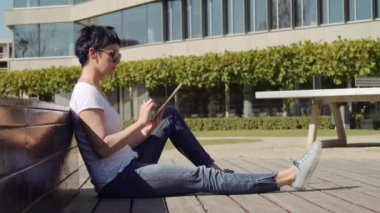 bina ve bir tablet üzerinde çalışan bir işyeri önünde oturan iş kadın