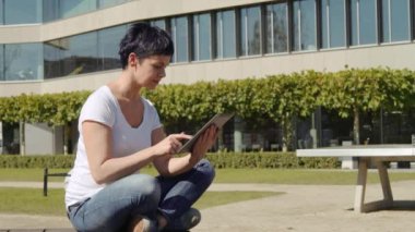 bina ve bir tablet üzerinde çalışan bir işyeri önünde oturan iş kadın