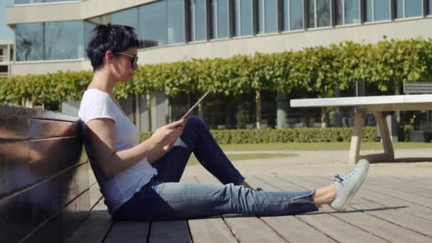 Obchodní žena sedí před kanceláří, budov a pracuje na tabletu — Stock video