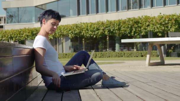 Geschäftsfrau sitzt vor einem Bürogebäude und arbeitet am Computer — Stockvideo