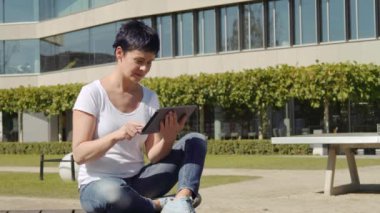 bina ve bir tablet üzerinde çalışan bir işyeri önünde oturan iş kadın