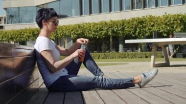 beyaz tişört bina ve portakal suyu içme bir ofis önünde oturan kadın