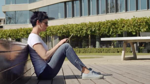 Femme d'affaires assise devant un immeuble de bureaux et travaillant sur une tablette — Video