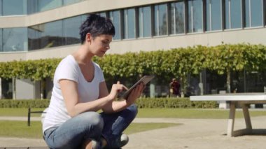 bina ve bir tablet üzerinde çalışan bir işyeri önünde oturan iş kadın