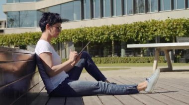 bina ve bir tablet üzerinde çalışan bir işyeri önünde oturan iş kadın