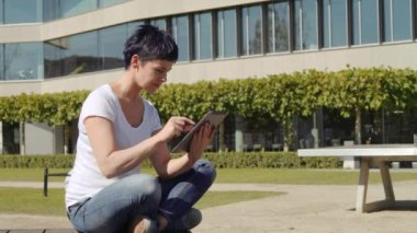bina ve bir tablet üzerinde çalışan bir işyeri önünde oturan iş kadın