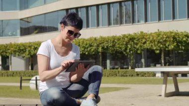 bina ve bir tablet üzerinde çalışan bir işyeri önünde oturan iş kadın