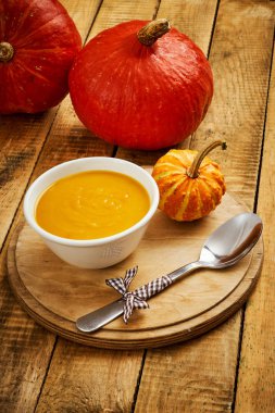 Eski bir ahşap mutfak masasında taze ve lezzetli balkabağı çorbası