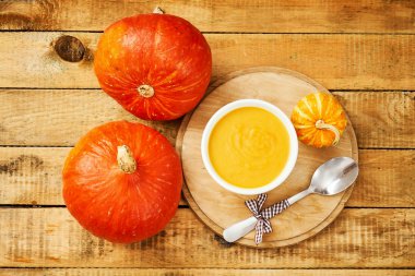 Eski bir ahşap mutfak masasında taze ve lezzetli balkabağı çorbası