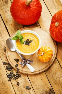 Eski bir ahşap mutfak masasında taze ve lezzetli balkabağı çorbası