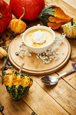 Eski bir ahşap mutfak masasında taze ve lezzetli balkabağı çorbası