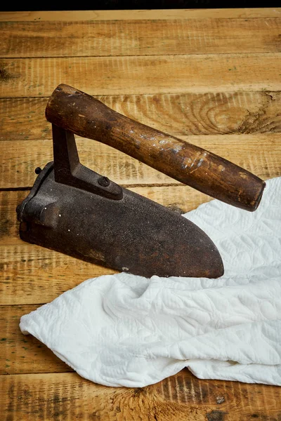 Ferro enferrujado velho e um pedaço de pano em uma mesa de madeira leve — Fotografia de Stock
