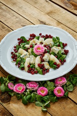 çiçekler ve armut gorgonzola peyniri ve marul üzerine beyaz bir tabak lezzetli bir salata