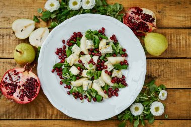 küçük çiçekler ve armut gorgonzola peyniri ve beyaz tabakta marul salata